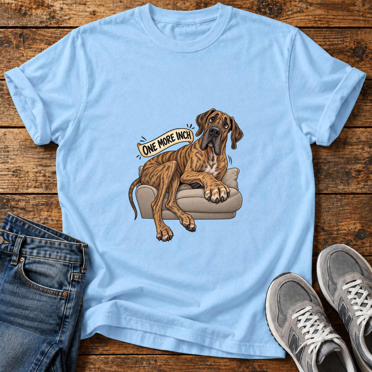 One More Inch Great Dane graphic T-shirt in Light Blue, shown on a flat-lay shirt mockup