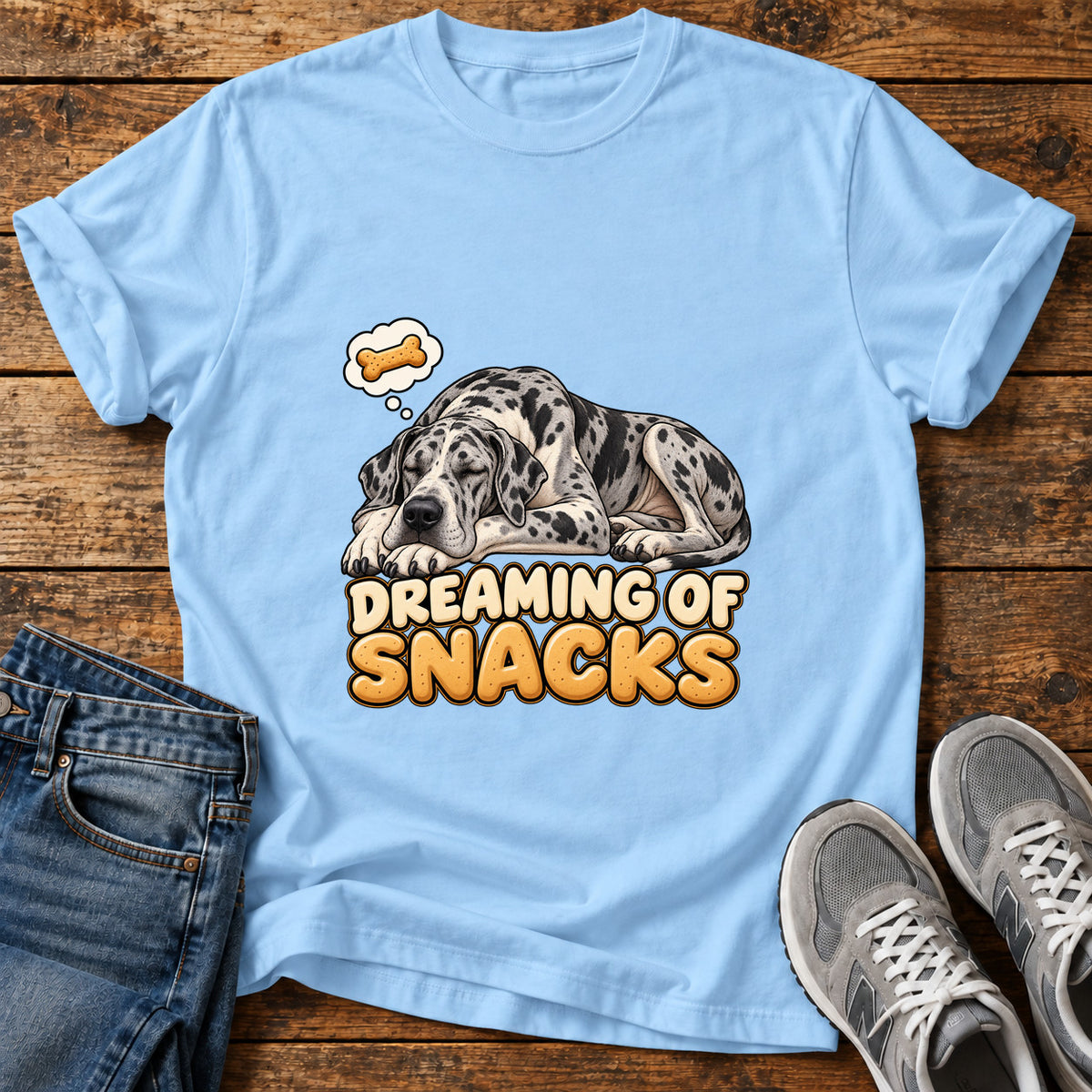Dreaming Snacks Great Dane graphic T-shirt in Light Blue, shown on a flat-lay shirt mockup