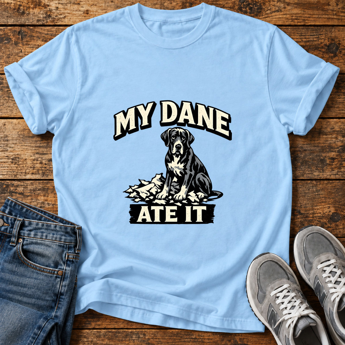 My Dane Ate Great Dane graphic T-shirt in Light Blue, shown on a flat-lay shirt mockup