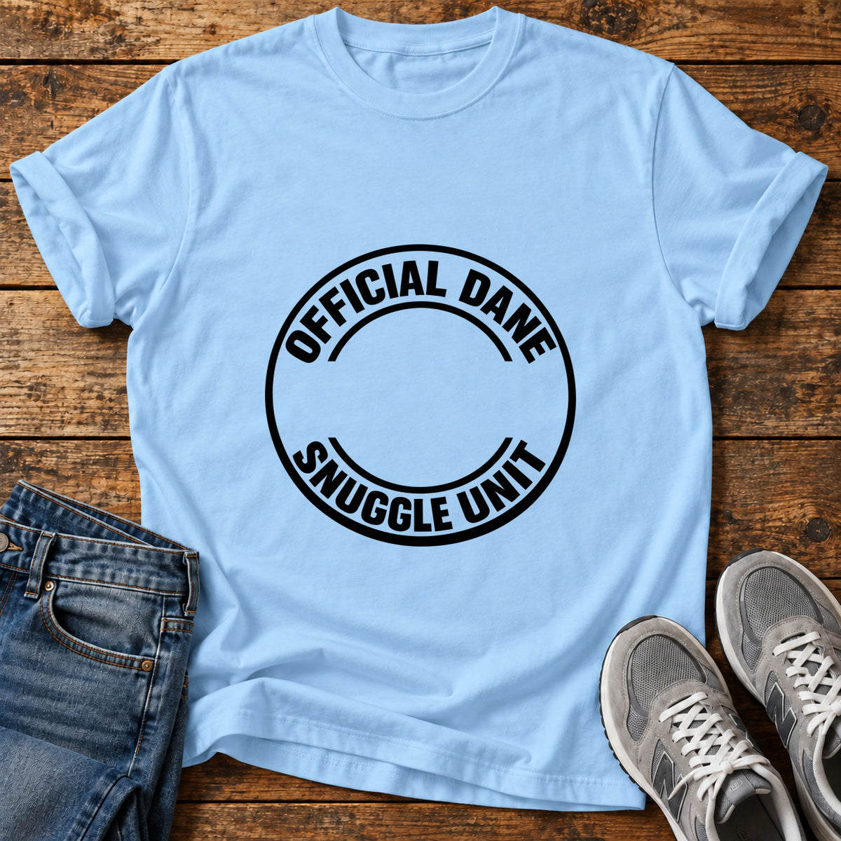 Dane Snuggle Badge Great Dane graphic T-shirt in Light Blue, shown on a flat-lay shirt mockup
