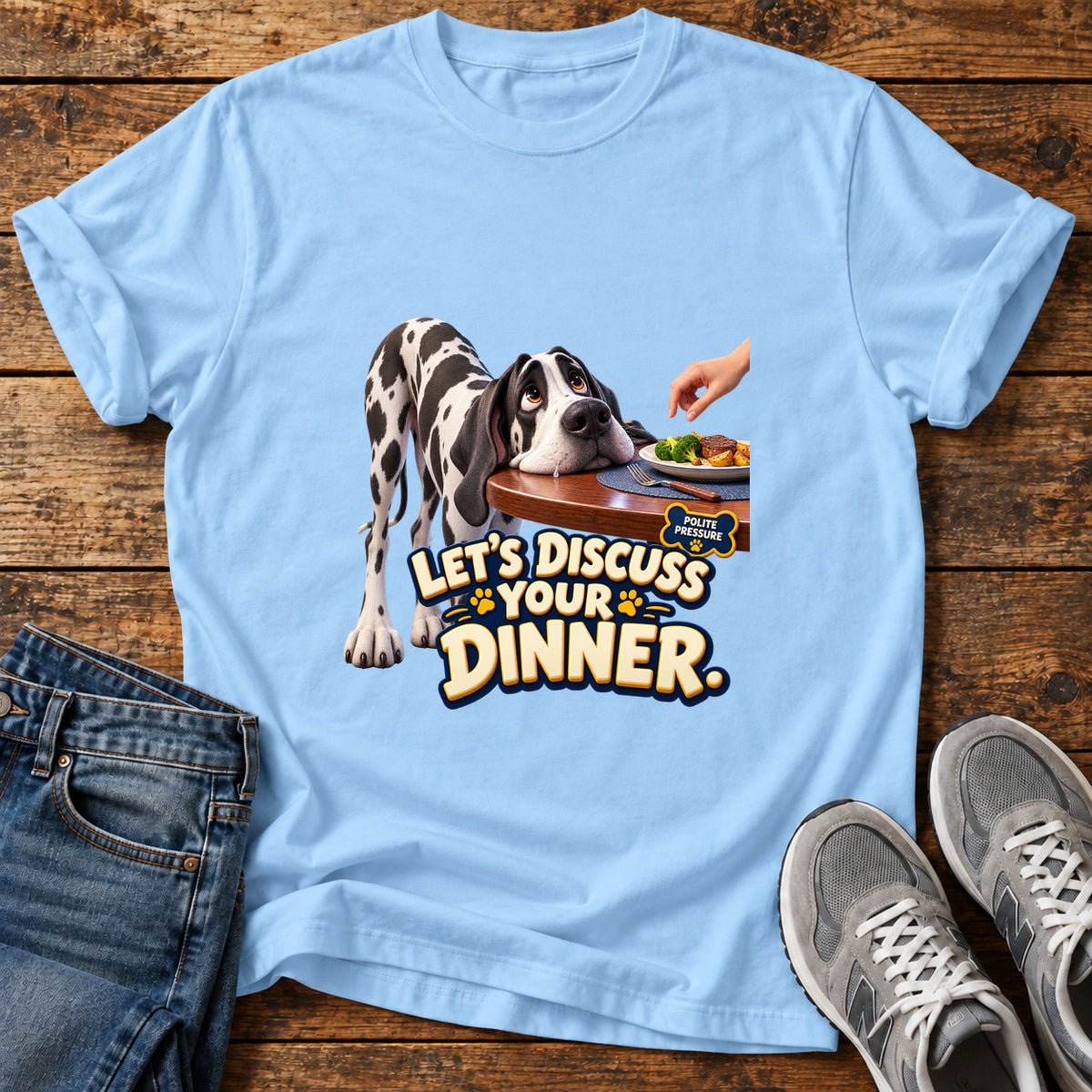 Discuss Your Dinner Great Dane graphic T-shirt in Light Blue, shown on a flat-lay shirt mockup