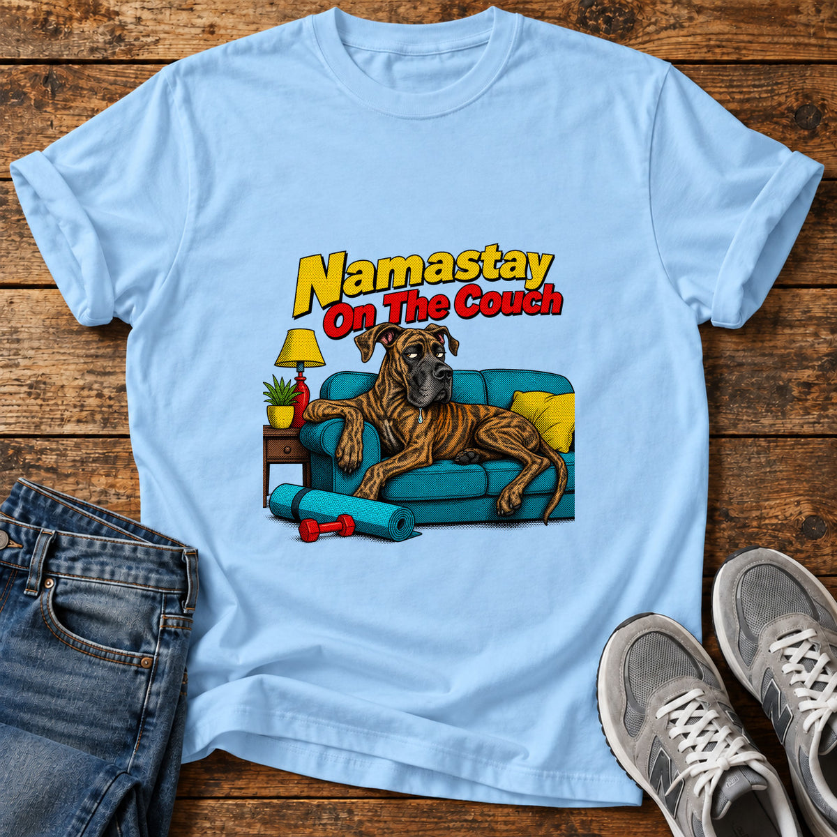 Namastay Couch Potato Great Dane graphic T-shirt in Light Blue, shown on a flat-lay shirt mockup
