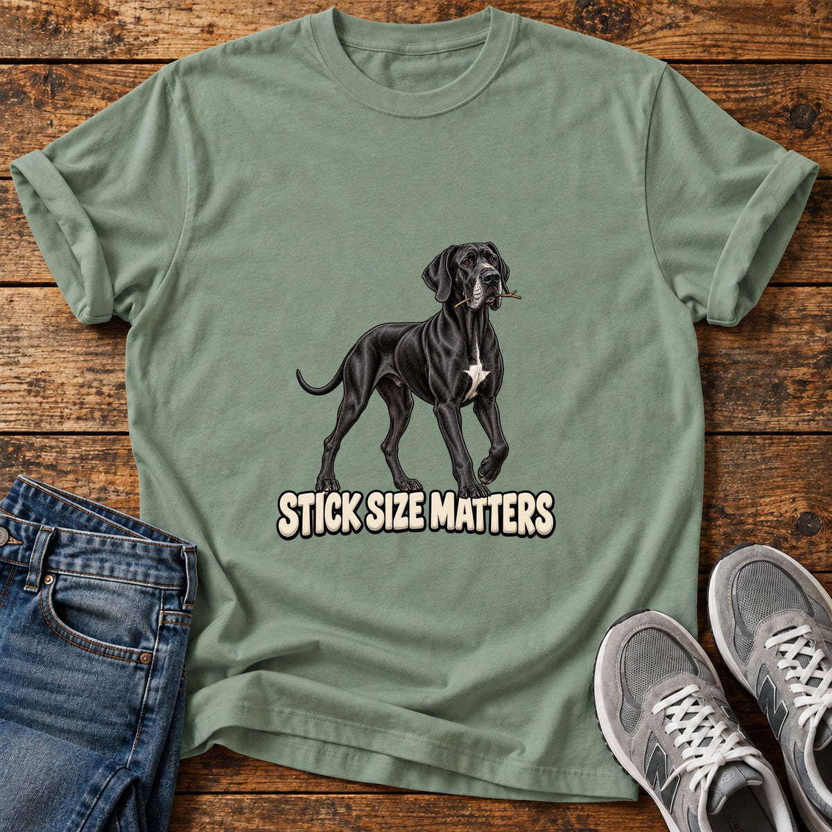 Stick Size Matters Great Dane graphic T-shirt in Sage, shown on a flat-lay shirt mockup