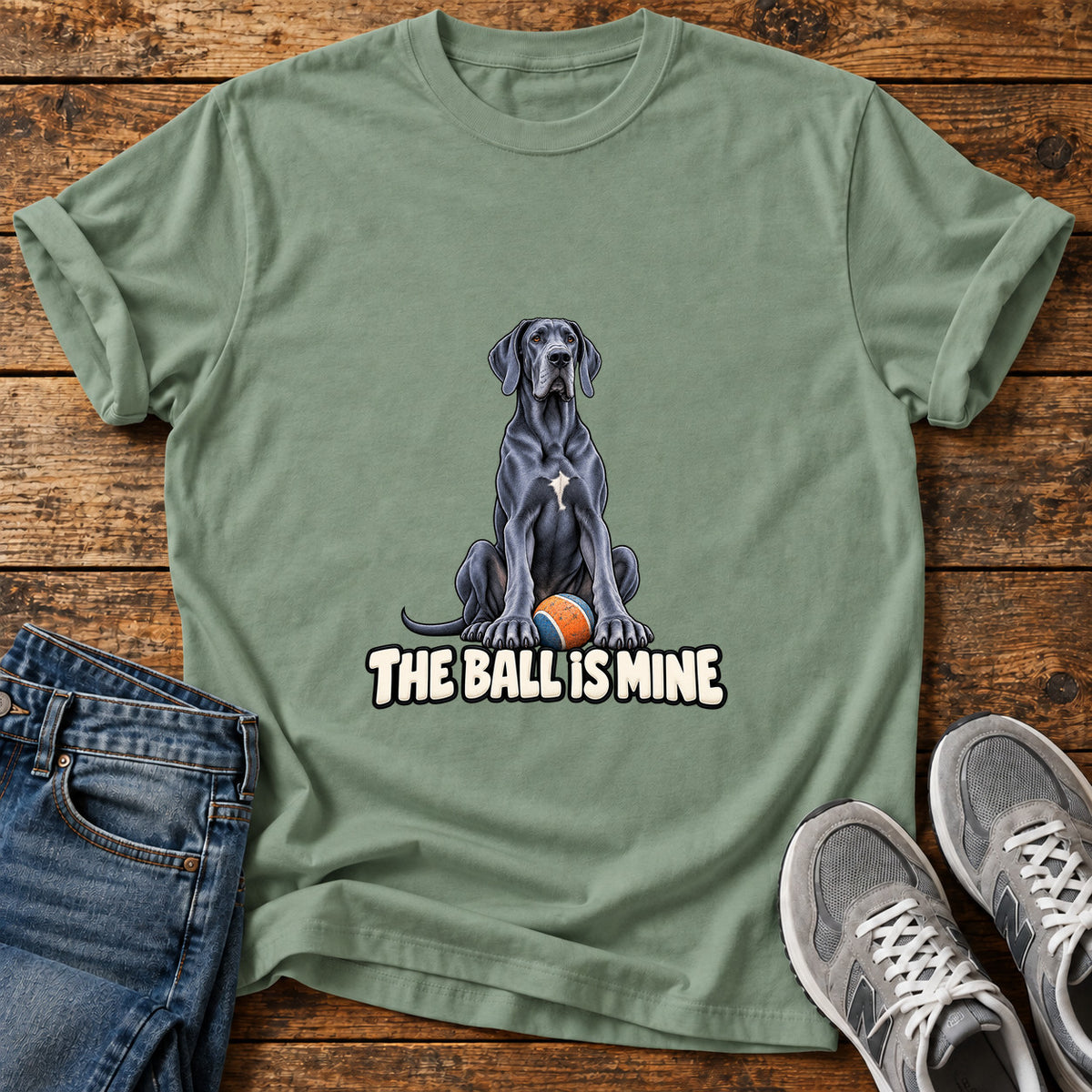 The Ball Is Great Dane graphic T-shirt in Sage, shown on a flat-lay shirt mockup