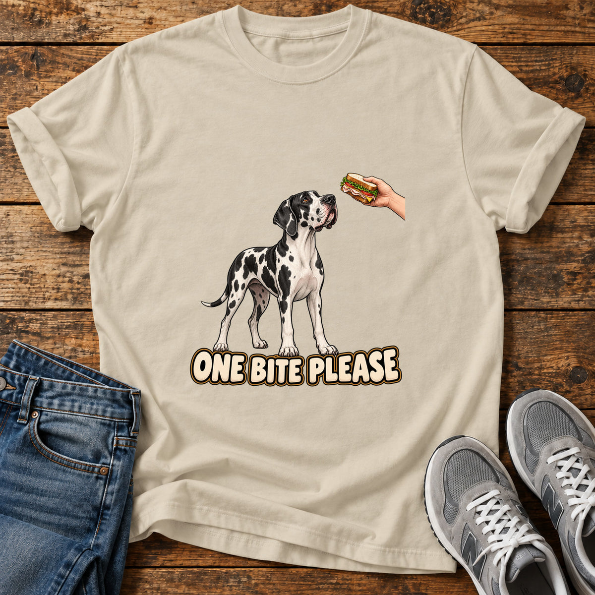 One Bite Please Great Dane graphic T-shirt in Sand, shown on a flat-lay shirt mockup