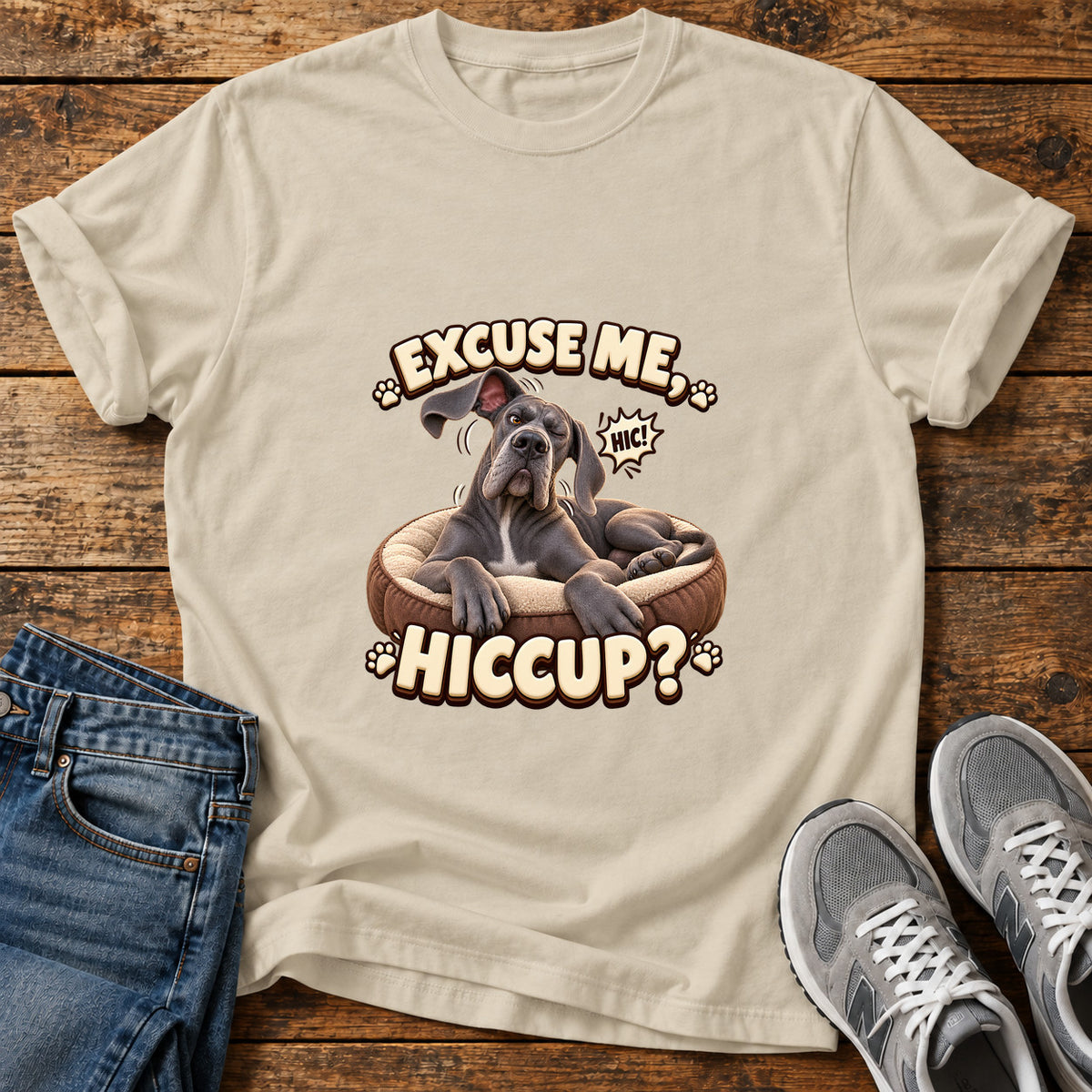 Excuse Hiccup Great Dane graphic T-shirt in Sand, shown on a flat-lay shirt mockup