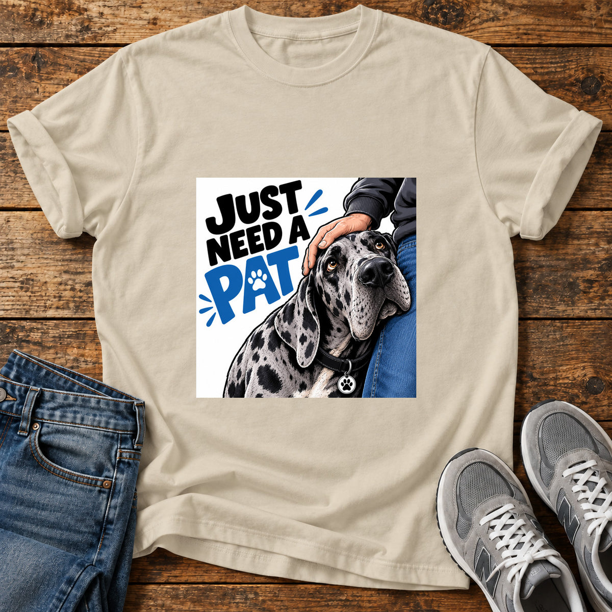 Just Need Pat Great Dane graphic T-shirt in Sand, shown on a flat-lay shirt mockup