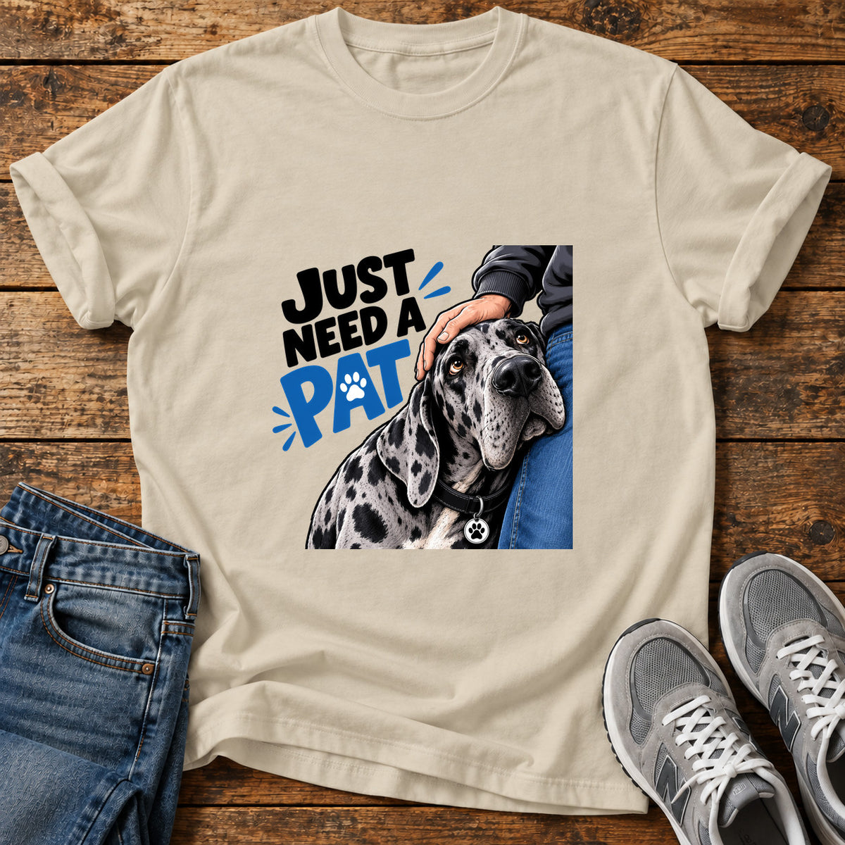 Just Need Pat Great Dane graphic T-shirt in Sand, shown on a flat-lay shirt mockup