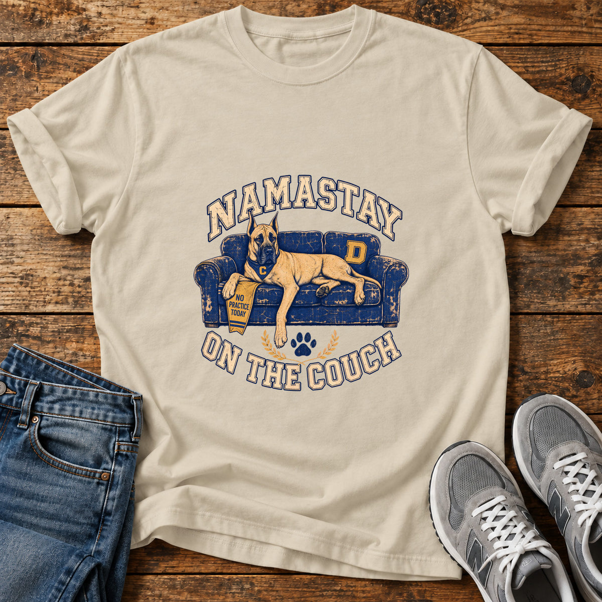 Namastay Couch Great Dane graphic T-shirt in Sand, shown on a flat-lay shirt mockup