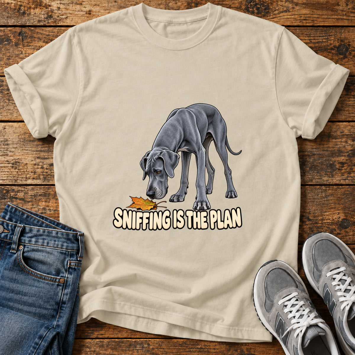 Sniffing Plan Great Dane graphic T-shirt in Sand, shown on a flat-lay shirt mockup