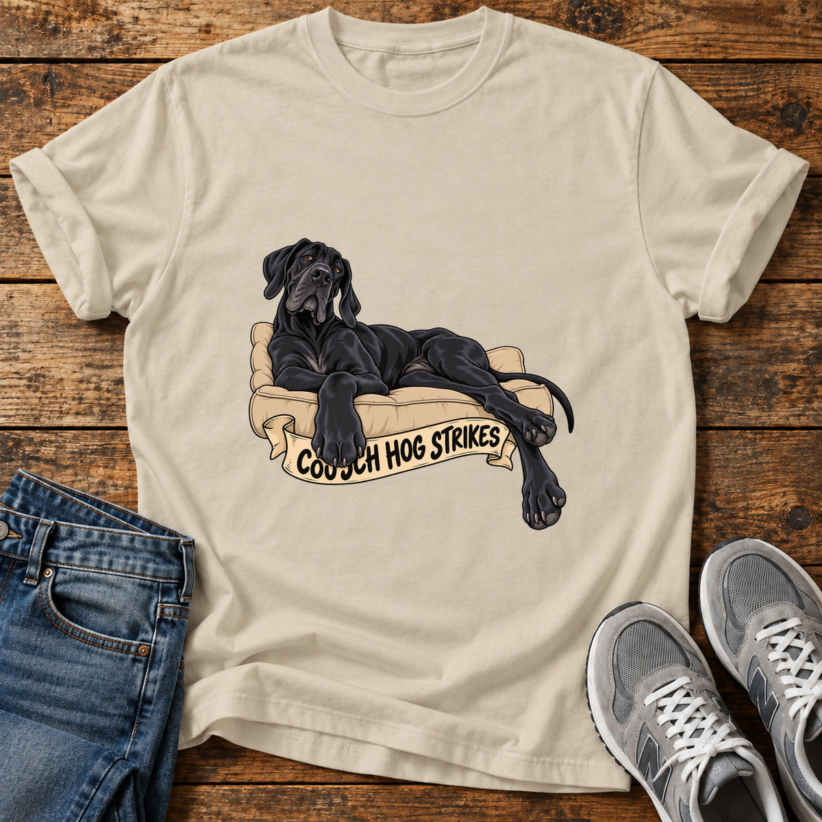 Couch Hog Strikes Great Dane graphic T-shirt in Sand, shown on a flat-lay shirt mockup