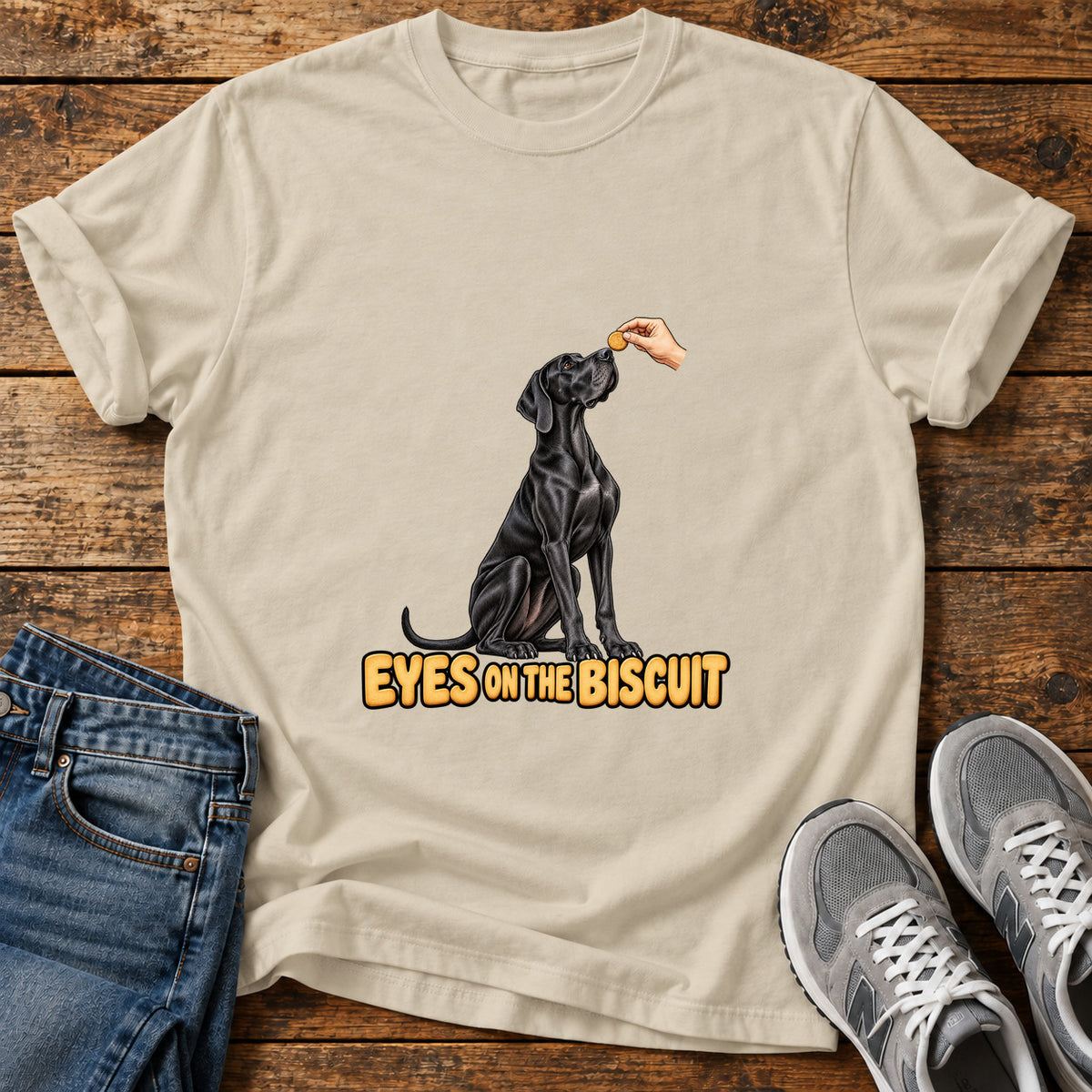 Eyes on Biscuit Great Dane graphic T-shirt in Sand, shown on a flat-lay shirt mockup