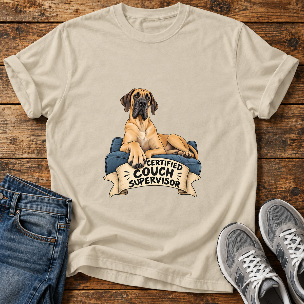 Certified Couch Supervisor Great Dane graphic T-shirt in Sand, shown on a flat-lay shirt mockup
