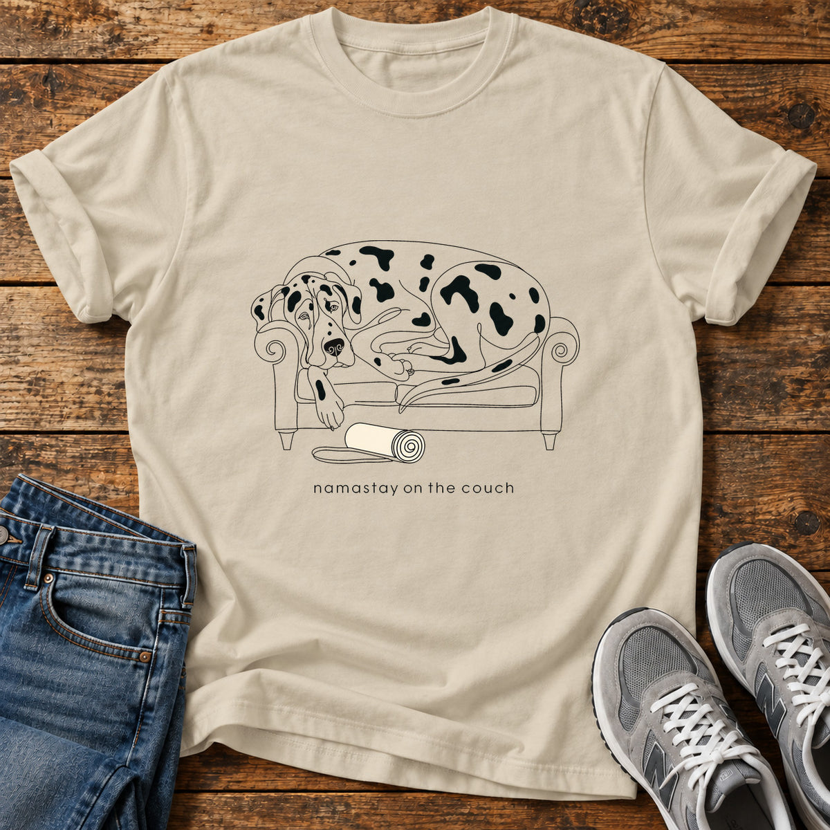 Namastay Couch Great Dane graphic T-shirt in Sand, shown on a flat-lay shirt mockup