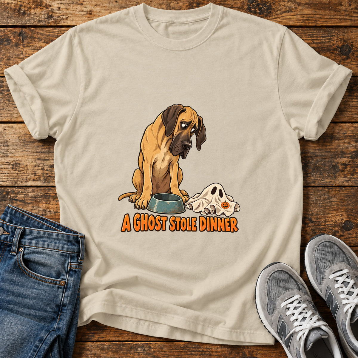 A Ghost Dinner Great Dane graphic T-shirt in Sand, shown on a flat-lay shirt mockup