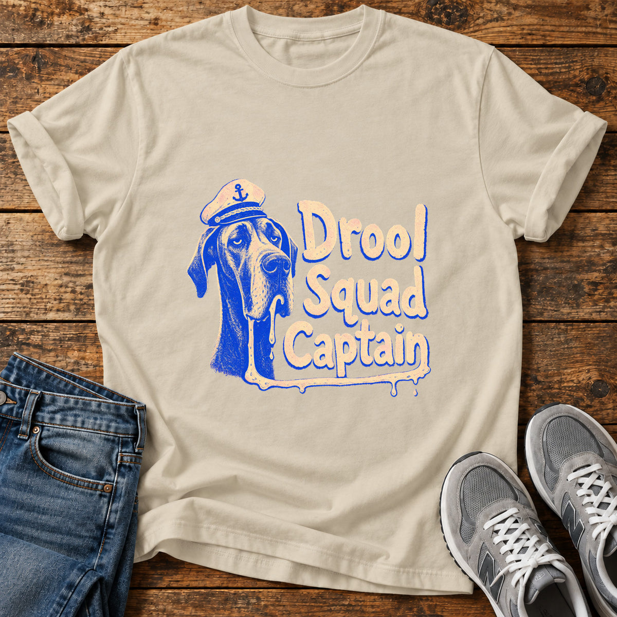 Drool Squad Captain Great Dane graphic T-shirt in Sand, shown on a flat-lay shirt mockup