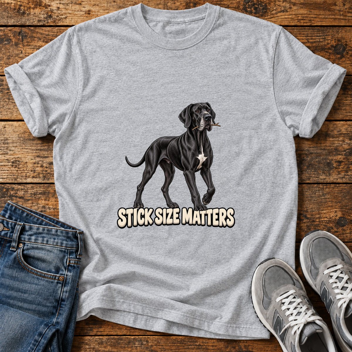 Stick Size Matters Great Dane graphic T-shirt in Sport Grey, shown on a flat-lay shirt mockup